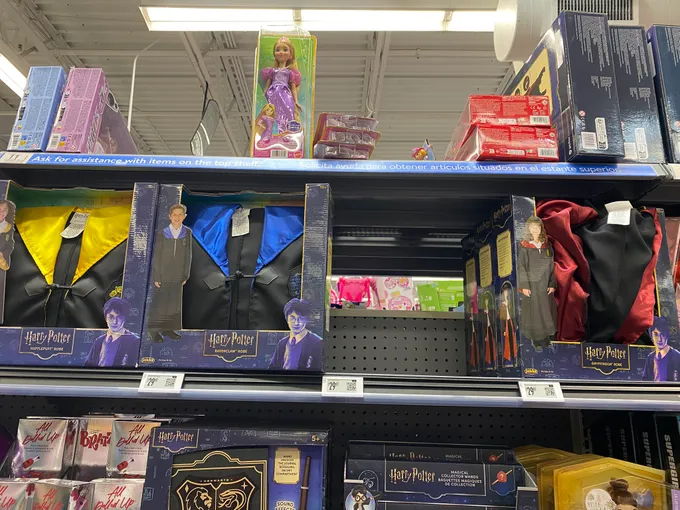 Photo of a store shelf with boxed Harry Potter house robes and an empty gap where Slytherin should be